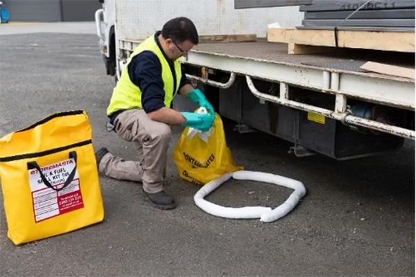 bộ chống tràn công nhân dọn dẹp chỗ rò rỉ từ xe tải bằng cần và túi đựng chất thải